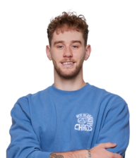Young man with curly hair and beard smiling in a blue sweater with We&#039;re the Force for Chaos print.